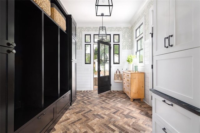 mudroom with crown molding and wallpapered walls