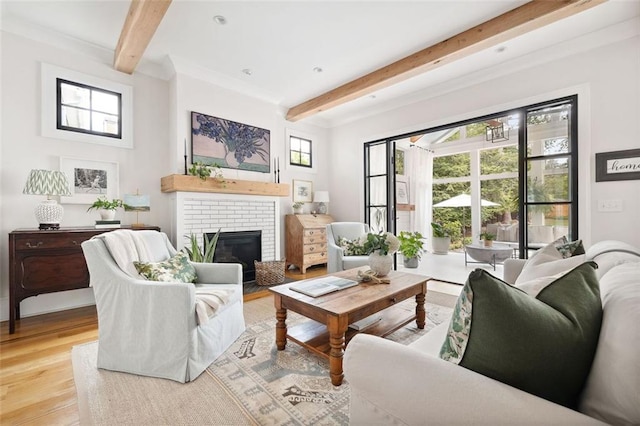 living area with a brick fireplace, a wealth of natural light, beam ceiling, and wood finished floors
