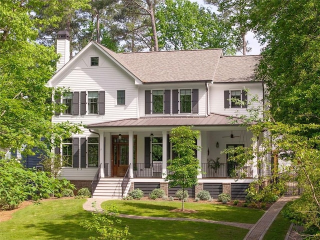 view of front of property featuring a porch, a chimney, a shingled roof, and a front yard