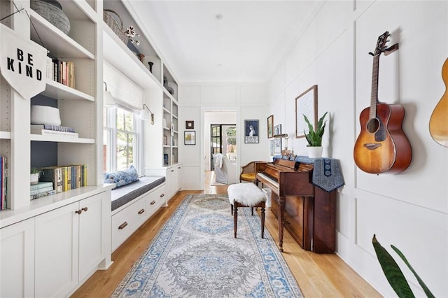 sitting room with ornamental molding and light wood finished floors