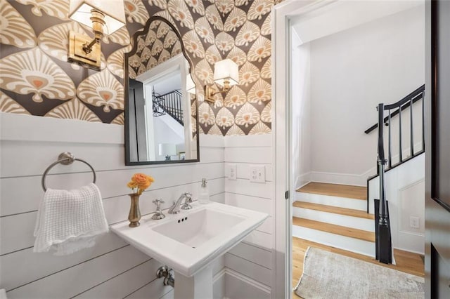 bathroom featuring baseboards, wood finished floors, and wallpapered walls