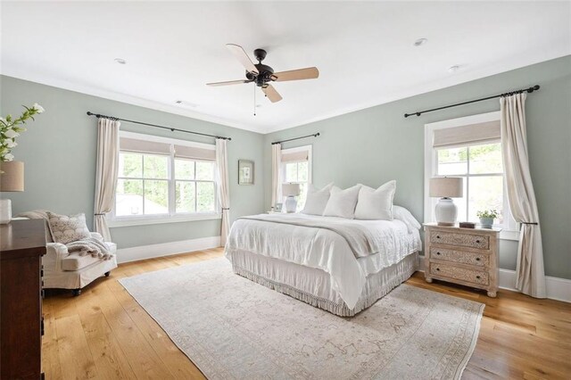 bedroom with crown molding, visible vents, baseboards, light wood-type flooring, and a ceiling fan