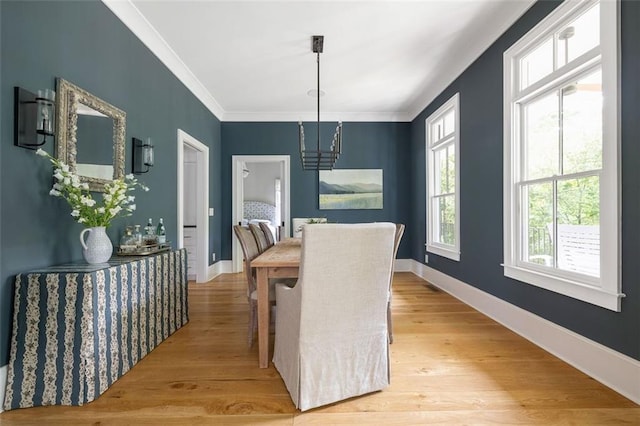 dining space with crown molding, baseboards, and light wood-type flooring