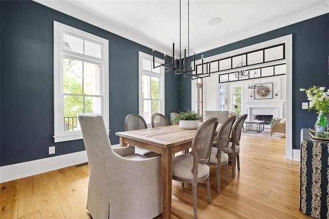 dining area featuring baseboards, light wood finished floors, a notable chandelier, and a wealth of natural light