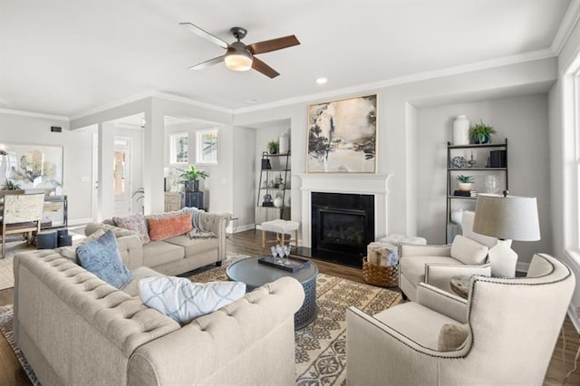 living room with dark wood-type flooring, ornamental molding, and ceiling fan