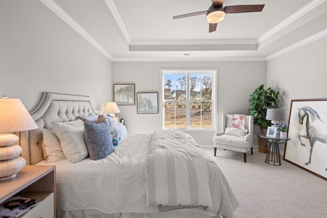 carpeted bedroom featuring a tray ceiling, ornamental molding, and ceiling fan