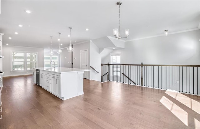 kitchen with hanging light fixtures, hardwood / wood-style flooring, and a kitchen island with sink