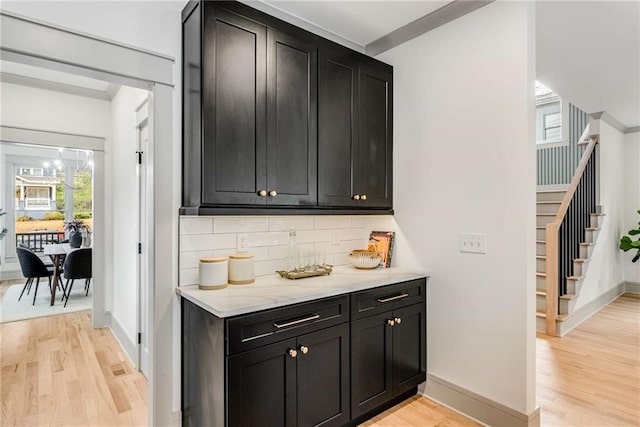 bar featuring baseboards, stairway, light wood-style flooring, and decorative backsplash