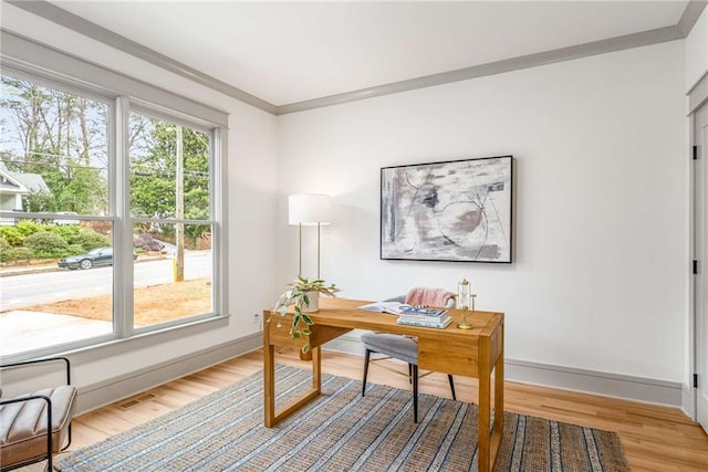 office featuring baseboards, crown molding, visible vents, and light wood finished floors