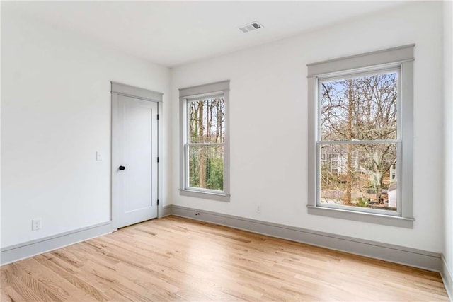 empty room featuring light wood-style floors, baseboards, and visible vents