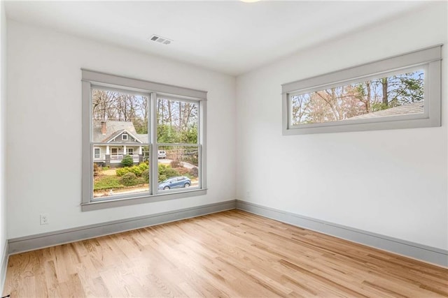 empty room with baseboards, wood finished floors, and a healthy amount of sunlight