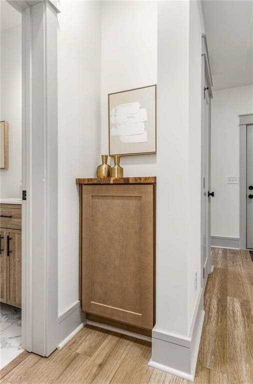 corridor with light wood finished floors and baseboards