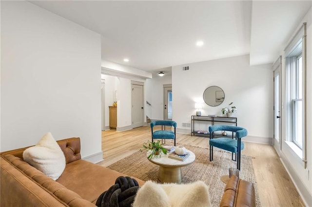 living area featuring a wealth of natural light, visible vents, and light wood-style floors