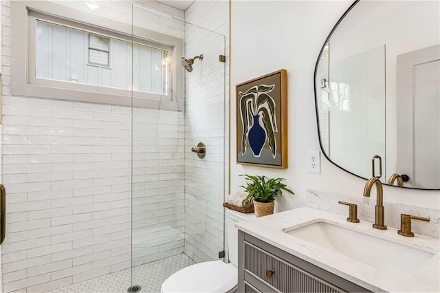 bathroom featuring vanity, a tile shower, and toilet