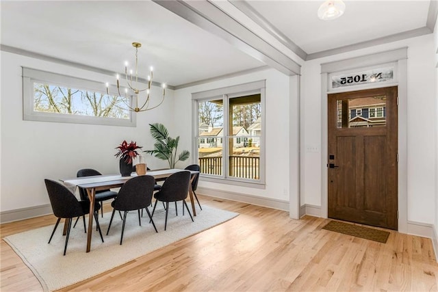 dining room with light wood finished floors, baseboards, a chandelier, and ornamental molding