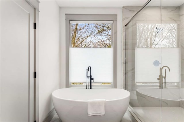 full bathroom featuring a freestanding tub and a marble finish shower