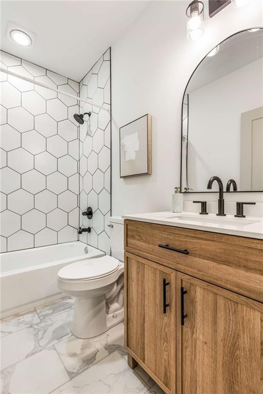 full bathroom with marble finish floor, tub / shower combination, vanity, and toilet