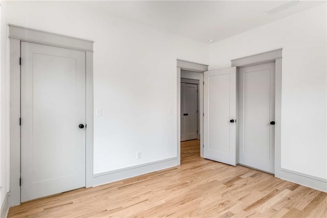 unfurnished bedroom featuring light wood-type flooring, visible vents, and baseboards