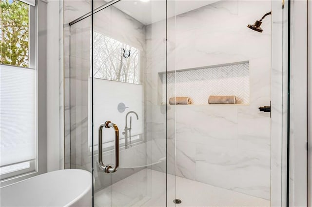 bathroom with a freestanding tub and a marble finish shower