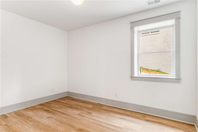 empty room featuring light wood-style flooring, visible vents, and baseboards