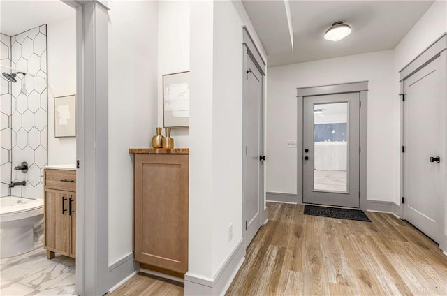 foyer with light wood-style flooring and baseboards