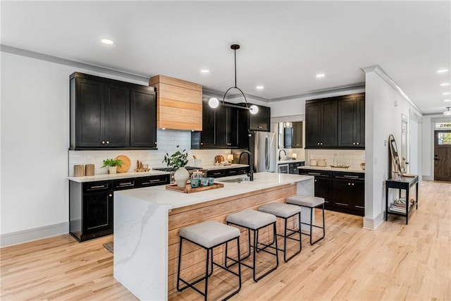 kitchen with dark cabinets, stainless steel appliances, light wood finished floors, and a breakfast bar area