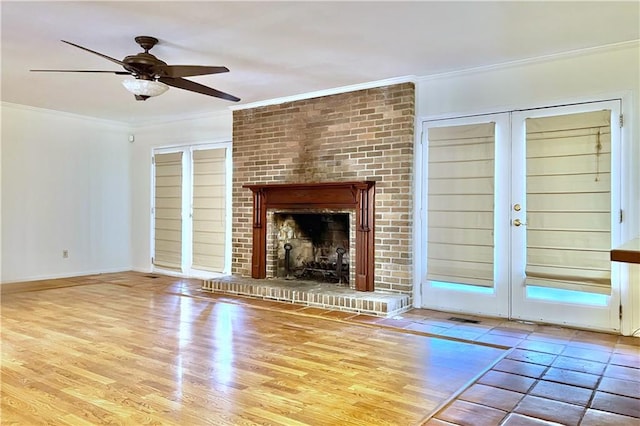 unfurnished living room featuring ceiling fan, french doors, a fireplace, and ornamental molding