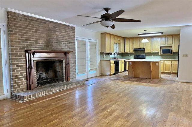 kitchen featuring decorative light fixtures, a brick fireplace, a center island, decorative backsplash, and light wood-type flooring