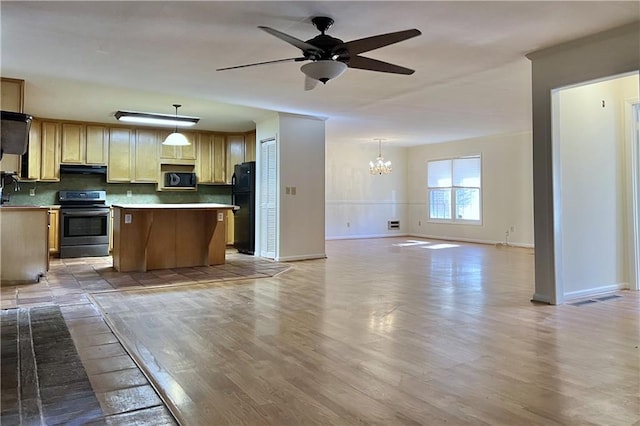 kitchen featuring pendant lighting, stainless steel electric stove, black refrigerator, and a kitchen island