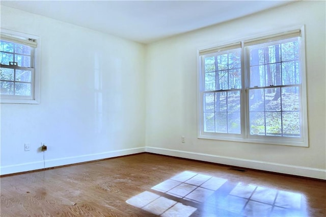 empty room with a healthy amount of sunlight and wood-type flooring