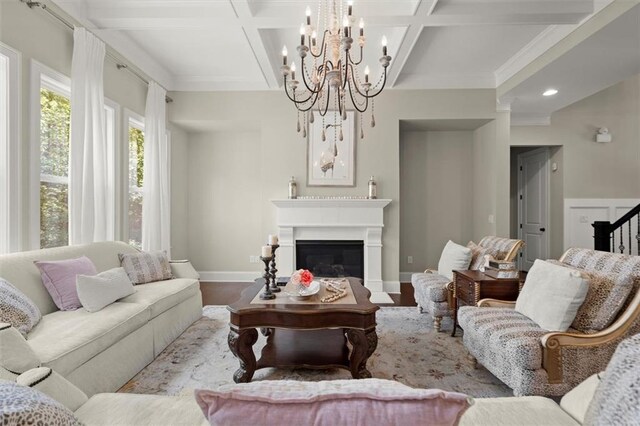 living room with an inviting chandelier, a glass covered fireplace, baseboards, wood finished floors, and coffered ceiling