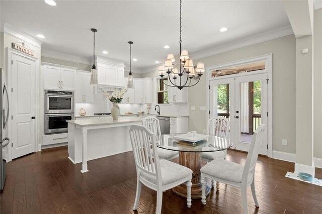 dining area with dark wood finished floors, ornamental molding, recessed lighting, and a notable chandelier