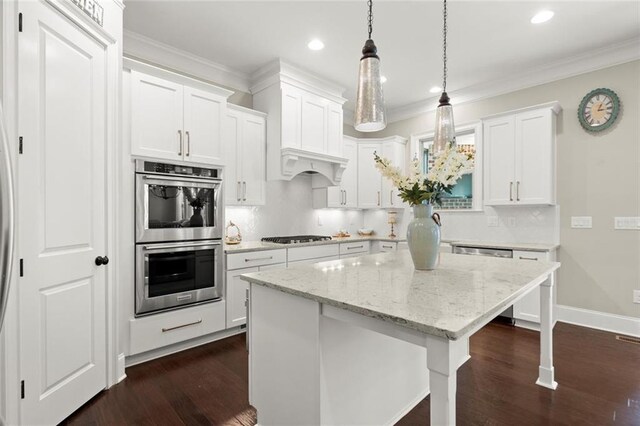 kitchen featuring crown molding, appliances with stainless steel finishes, a kitchen island, and dark wood-style floors
