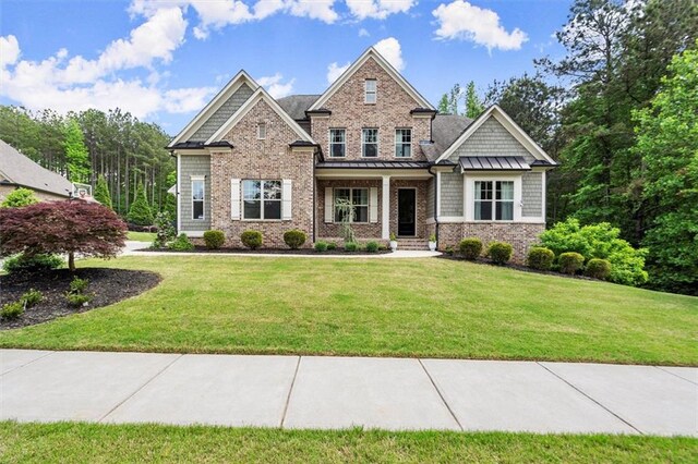 craftsman house featuring a front lawn, covered porch, and a standing seam roof
