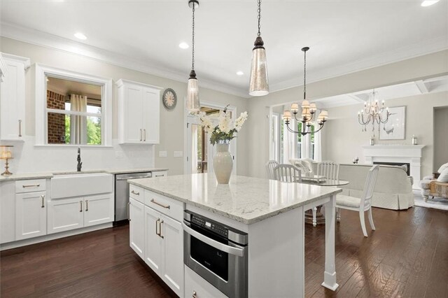 kitchen featuring open floor plan, a center island, white cabinetry, a sink, and stainless steel appliances