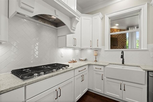kitchen featuring decorative backsplash, a sink, stainless steel gas stovetop, ornamental molding, and white cabinetry
