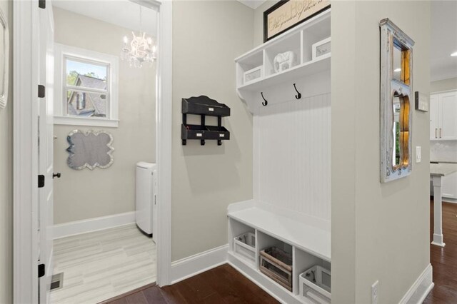 mudroom featuring an inviting chandelier, baseboards, dark wood finished floors, and washer and dryer