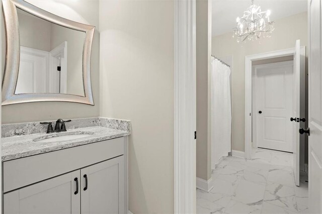 bathroom featuring baseboards, an inviting chandelier, marble finish floor, and vanity