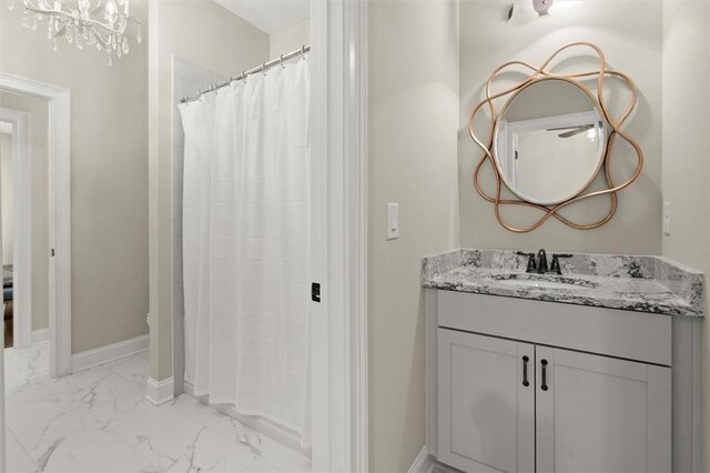 full bath featuring vanity, marble finish floor, baseboards, and curtained shower