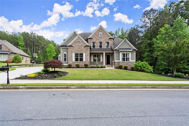 craftsman house featuring metal roof, stone siding, a front yard, and a standing seam roof
