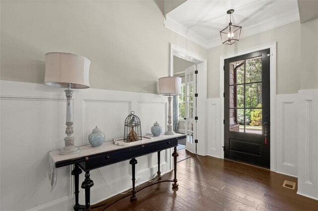 entrance foyer featuring dark wood-style flooring, wainscoting, a decorative wall, visible vents, and ornamental molding