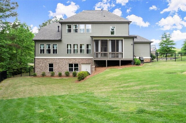 back of property featuring a fenced backyard, a lawn, a sunroom, and roof with shingles