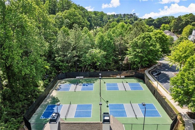 view of sport court with fence and a forest view