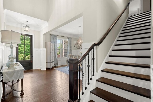 foyer entrance with stairway, a healthy amount of sunlight, hardwood / wood-style floors, and a notable chandelier