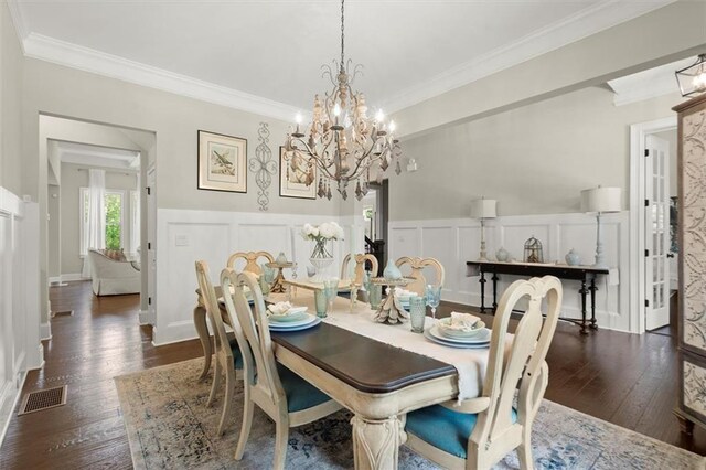 dining area with a notable chandelier, visible vents, ornamental molding, and a decorative wall