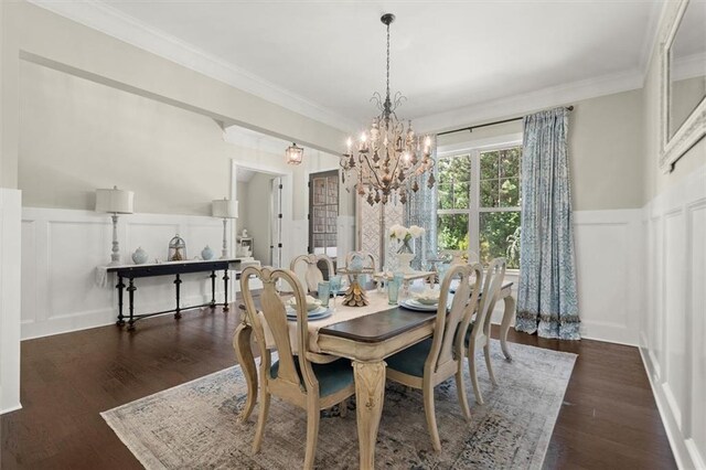 dining area featuring an inviting chandelier, crown molding, wood finished floors, a decorative wall, and a wainscoted wall