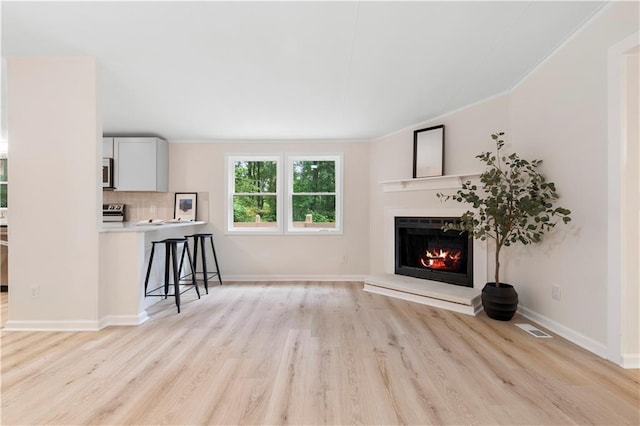 1010 Martin Ln, Canton, GA 30114 - unfurnished living room featuring ornamental molding, a lit fireplace, and light wood-style floors