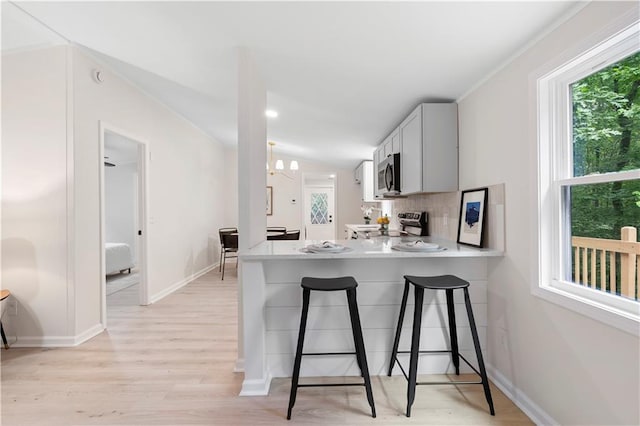 1010 Martin Ln, Canton, GA 30114 - kitchen with stainless steel microwave, stove, light wood-style floors, a kitchen breakfast bar, and light countertops