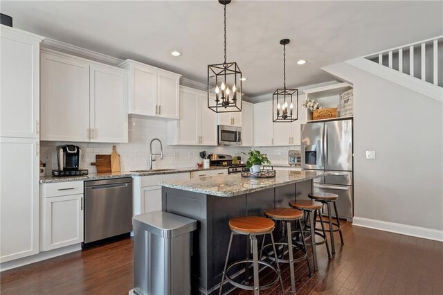 kitchen with appliances with stainless steel finishes, a sink, dark wood-type flooring, a center island, and a breakfast bar area