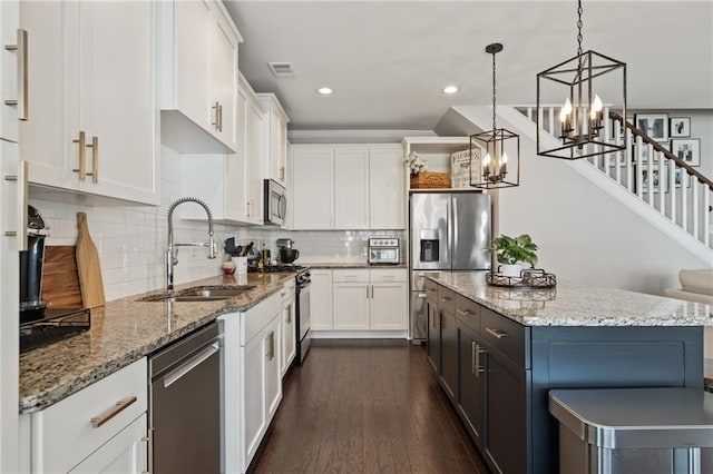 kitchen with stainless steel appliances, a sink, a chandelier, a kitchen island, and white cabinets